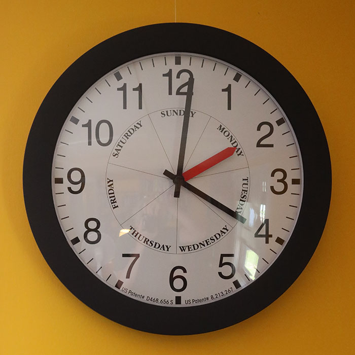 Round Clock with Day of the Week Hand on Yellow Wall